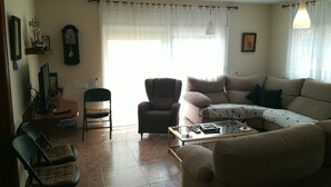 A living room with a sofa, armchair, and a coffee table. There is a clock on the wall and a window with curtains. - Large house with private garden / pool at 1500 meters from the sea (Playa de Aro) (Calonge)