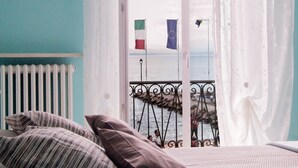 Ein Schlafzimmer mit Bett, Kissen, Meerblick und einem Balkon mit Geländer.
