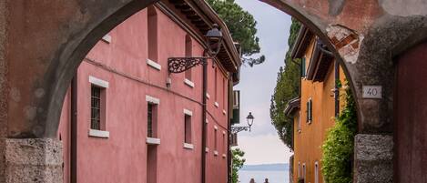 An arched stone gateway leading to a cobblestone street flanked by buildings with traditional architecture.