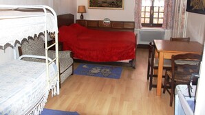 Quarto com beliche, escrivaninha, cadeira, luminária e duas pinturas nas paredes.