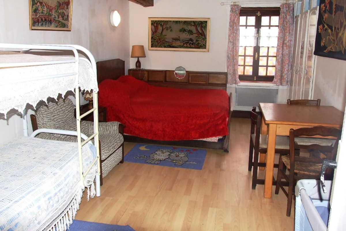A room with a bunk bed, a desk, a chair, a lamp, and two paintings on the walls.
