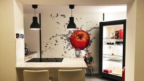Eine moderne Küche mit einer zentralen Kochinsel, zwei Pendelleuchten und einem Kühlschrank mit Glastür.
