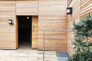A wooden building with a large open doorway, a metal gate, and a potted plant.