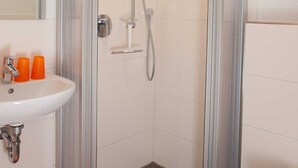 Une douche avec une porte en verre, un lavabo avec un miroir et des toilettes.
