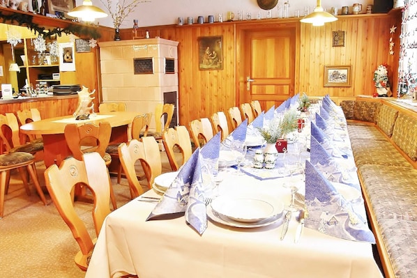 A dining area with a long table set for a meal, wooden chairs, and a bench along the wall.