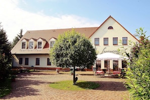 A hotel with a traditional architectural style, featuring a central courtyard with a tree and outdoor seating area.