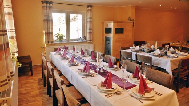 Un espace repas avec des tables dressées pour le service, agrémenté de nappes blanches et de serviettes rouges.
