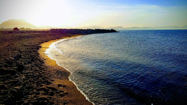 Una spiaggia con un litorale roccioso e acque calme.