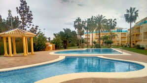 Una piscina dalle linee curve, un gazebo e un edificio con balconi.