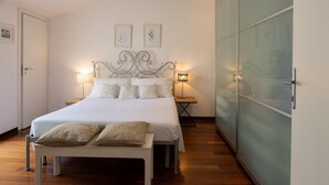 A neatly arranged bedroom with a bed, bedside tables, and a bench. - Villa Carlino White (Mascali)