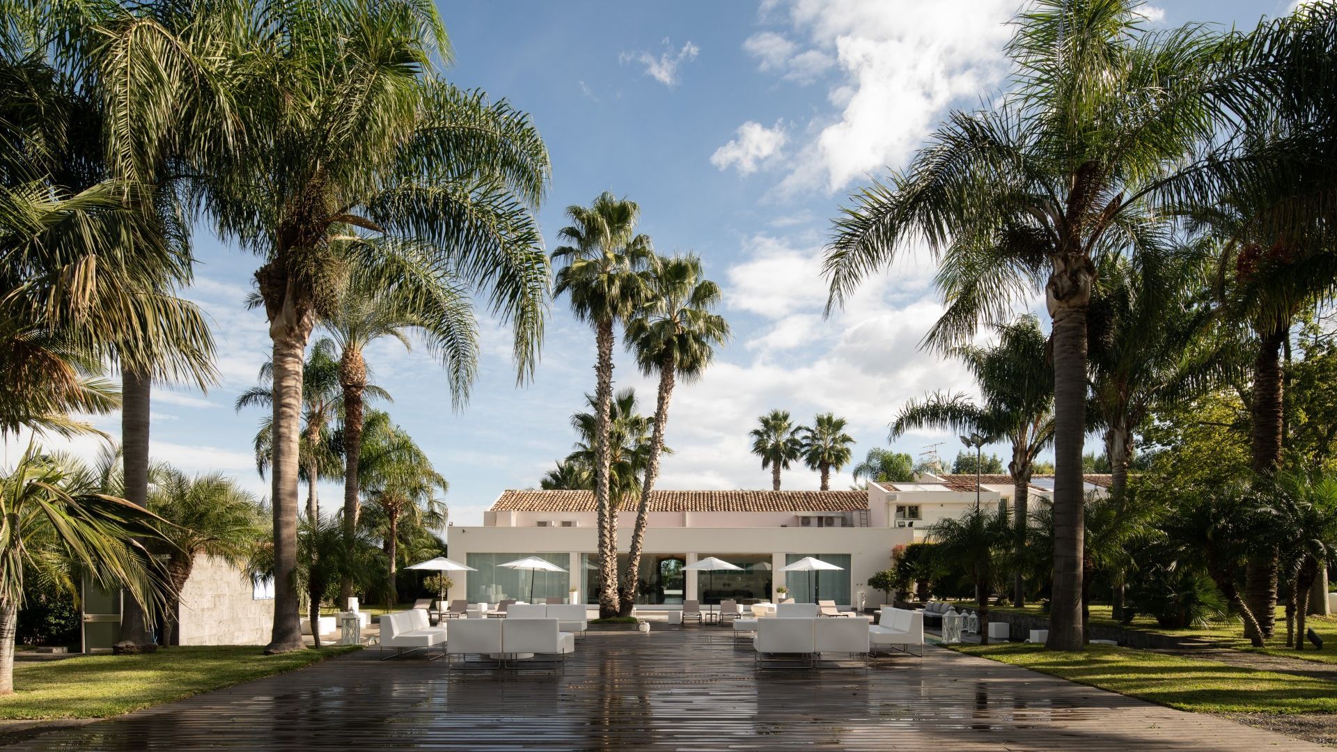 Un resort con area piscina, palme e posti a sedere all'aperto.