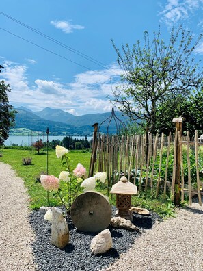 Een tuin met een grindpad, een houten hek en uitzicht op bergen.