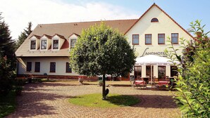 Un hotel de estilo arquitectónico tradicional, con un patio central que tiene un árbol y un área de estar al aire libre.