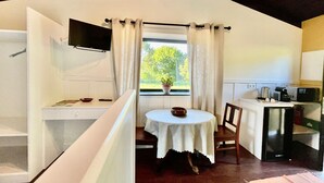Una habitació acollidora amb taula de menjador, una cuineta i una finestra amb cortines.