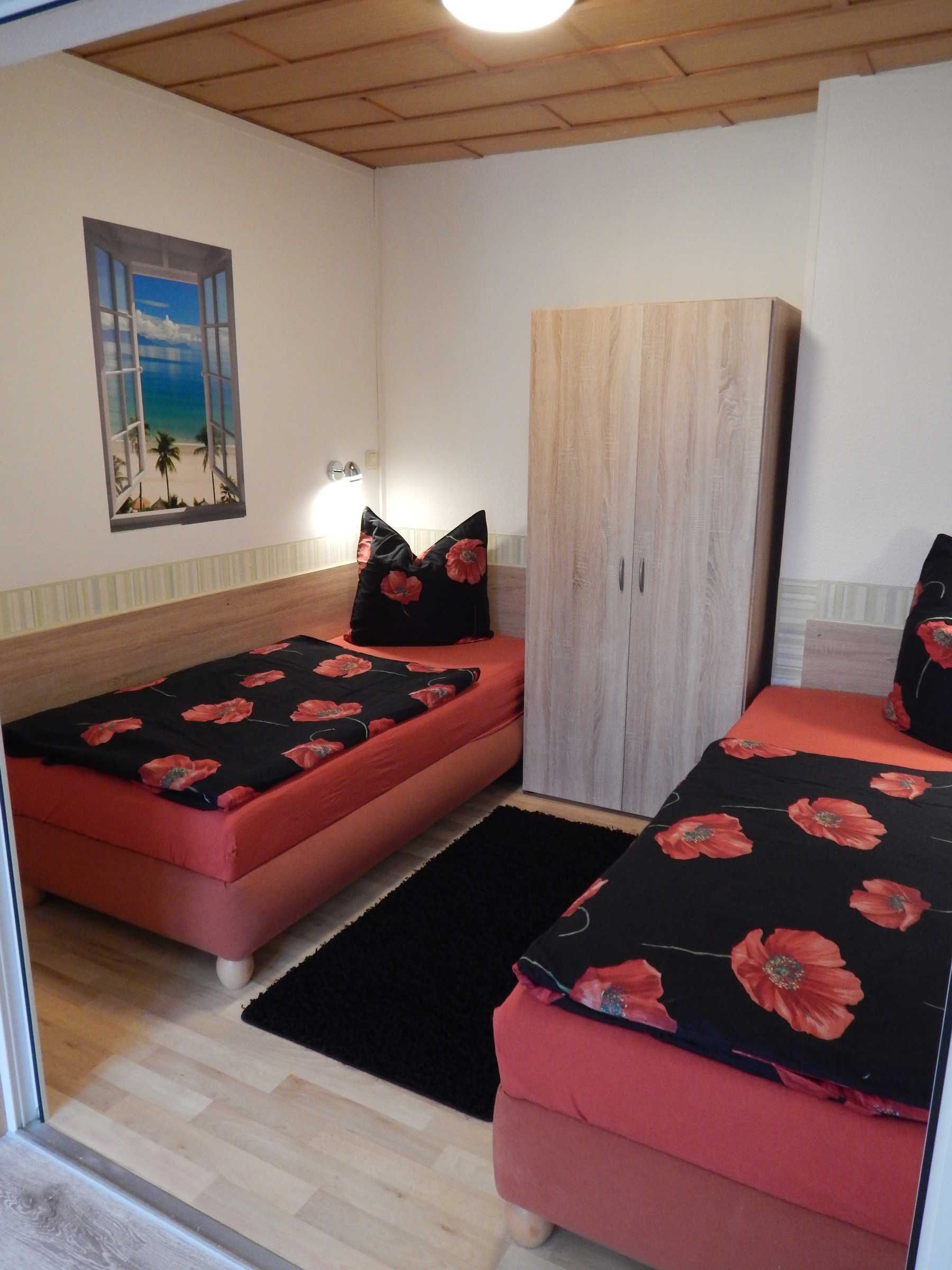 Une chambre avec deux lits, une armoire et un mur décoré d’une scène de plage.