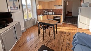 A compact kitchen with wooden cabinets, a dining table, and a TV on a cabinet. - Cozy getaway with garden and Wi-Fi, romantic retreat (Saint-André-d'Apchon)