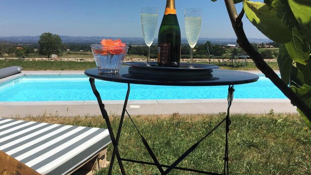 A poolside table with a bottle of champagne, two glasses, and a flower in a glass bowl. - Cozy getaway with garden and Wi-Fi, romantic retreat (Saint-André-d'Apchon)