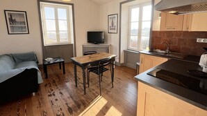 A compact kitchen with a wooden table, a built-in stove, and a window overlooking a snowy landscape. - Cozy getaway with garden and Wi-Fi, romantic retreat (Saint-André-d'Apchon)