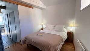 A bedroom with a bed, two bedside lamps, a radiator, and a wooden floor. - Cozy getaway with garden and Wi-Fi, romantic retreat (Saint-André-d'Apchon)