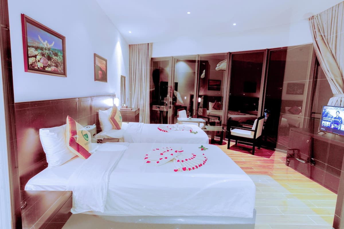 A hotel room with two beds, a TV, a desk, and a chair.