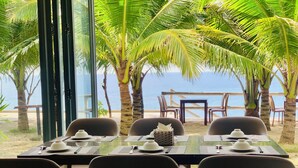 Una mesa lista para comer, con vista al océano y palmeras.