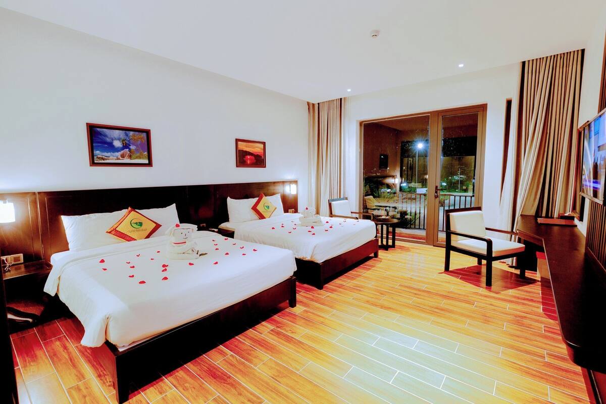 A hotel room with two beds, a TV, a chair, and a balcony with a view.