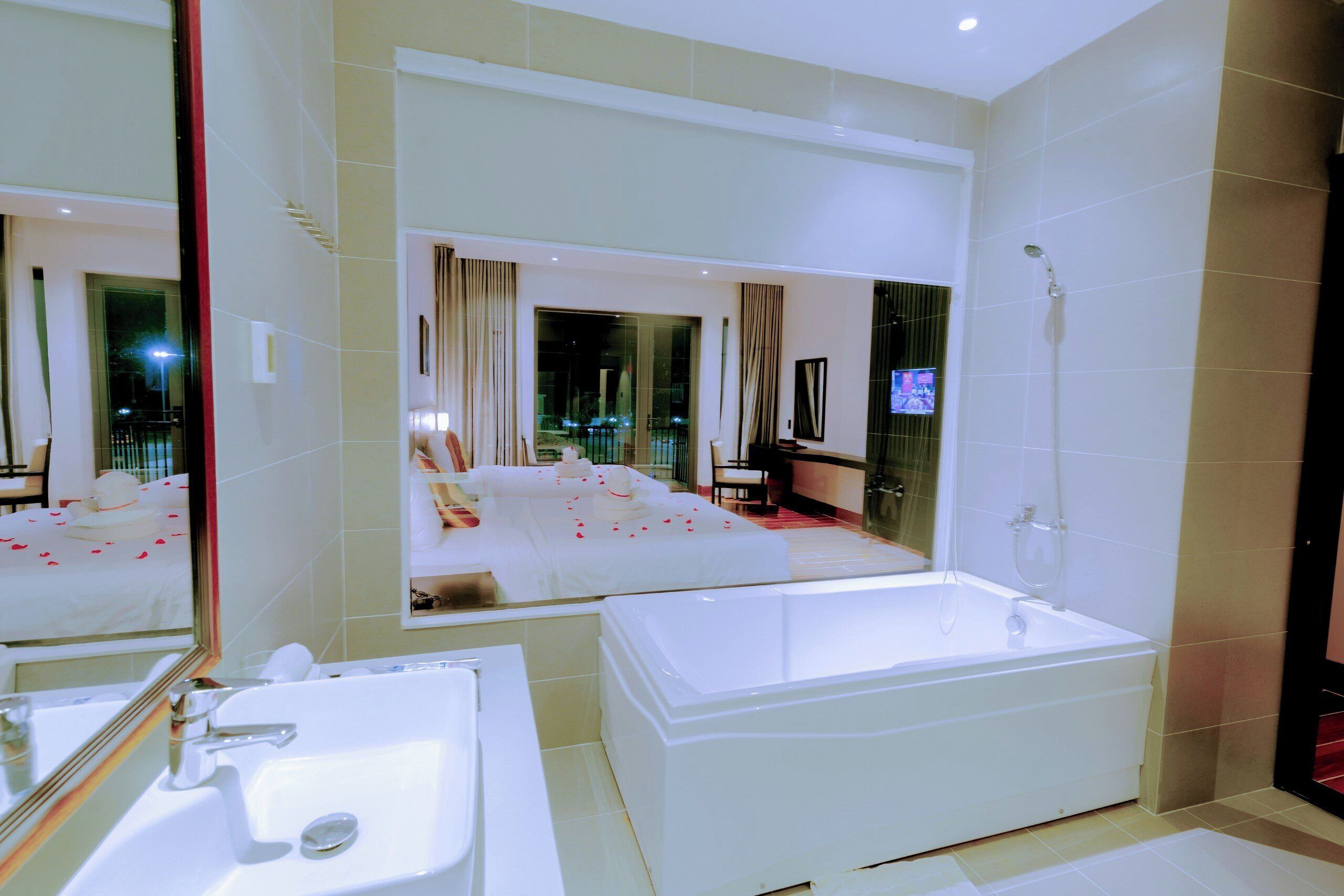 Un baño moderno con un espejo grande, una bañera y un lavamanos.