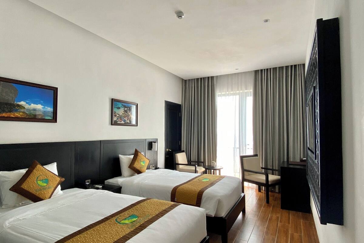 A hotel room with two beds, a desk, and a chair.