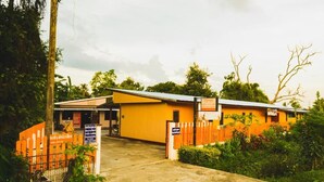 A building with a yellow exterior and a gated entrance. - Bannkrithamed Chiangmai (Hang Dong)