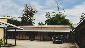 A building with a covered parking area, a motorcycle, and a truck parked in front. - Bannkrithamed Chiangmai (Hang Dong)