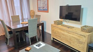 Un coin repas comprenant une table, des chaises, un téléviseur et un meuble en bois.