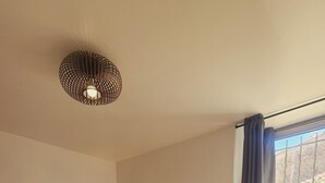 Une chambre à coucher avec un grand lit, une lampe de chevet, une fenêtre avec des rideaux et un plancher en bois.