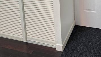 Ein Zimmer mit einer weißen Tür, einer schwarzen Fußmatte und einer Wand mit Muster.