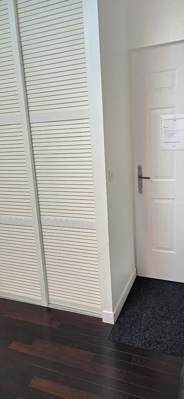 A room with a white door, a black doormat, and a patterned wall.