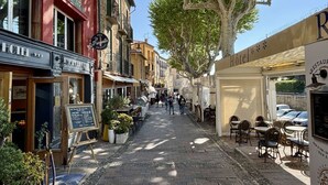 Uma rua estreita ladeada por edifícios, incluindo um hotel com a placa 