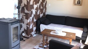 A cozy living room with a modern fireplace, a sofa, a coffee table, and a cowhide wall.