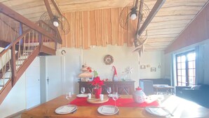 A dining area with a wooden table set for four, a staircase, and a view of the living room.