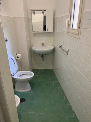 A small bathroom with a toilet, sink, and mirror. - Casa Rosy (Naples)