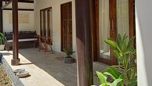 A covered outdoor area with a wooden pergola, a bench, and potted plants. - Vila Bukit Sari (Buleleng)