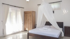 A bedroom with a wooden bed, white curtains, and a wooden wardrobe. - Vila Bukit Sari (Buleleng)