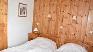 Quarto com duas camas, cabeceira de madeira, duas mesas de cabeceira com luminárias e um quadro na parede.
