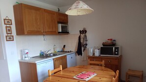 A compact kitchen with wooden cabinets, a microwave, a coffee maker, and a dining table with chairs. - Studio cabin 4 pers, mountain view, ski access (La Joue du Loup)
