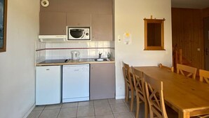 Una cocina compacta equipada con microondas, un refrigerador pequeño, lavavajillas y una mesa de comedor con sillas.