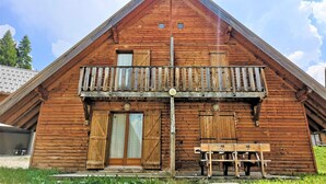 A wooden cabin with a balcony, a door, and a bench.