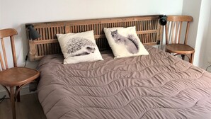 A bed with a beige quilt, two pillows with hedgehog designs, and a wooden headboard.