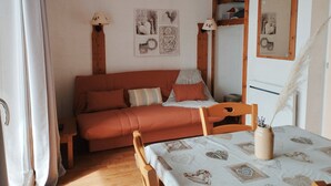 A cozy room with a wooden bed, a small table with a vase, and a mirror on the wall. - Studio cabin La Joue du Loup, 4 ppl., terrace, parking (La Joue du Loup)