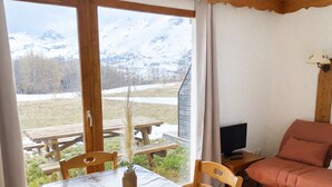 A room with a table, chairs, a sofa, a TV, and a view of mountains. - Studio cabin La Joue du Loup, 4 ppl., terrace, parking (La Joue du Loup)