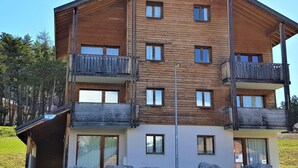 A multi-story wooden building with balconies, large windows, and a sign indicating a ski resort. - Studio cabin La Joue du Loup, 4 ppl., terrace, parking (La Joue du Loup)