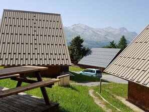 A mountain lodge with a wooden exterior, a picnic table, and a car parked in front. - Duplex chalet 3 rooms for 7 pers. with terrace and free parking (La Joue du Loup)
