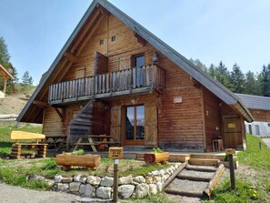 A wooden cabin with a balcony, a staircase, and a stone foundation. - Duplex chalet 3 rooms for 7 pers. with terrace and free parking (La Joue du Loup)